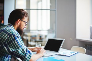 Modern businessman sitting at workplace and typing