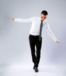 Businessman walking on invisible rope on gray background